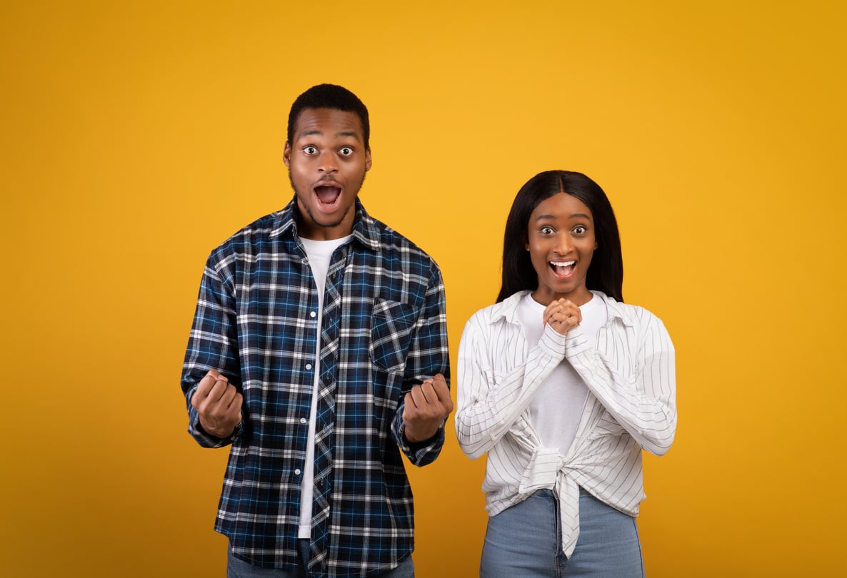 Excited millennial african american couple in love with wide open eyes and mouths, expresses emotions of victory